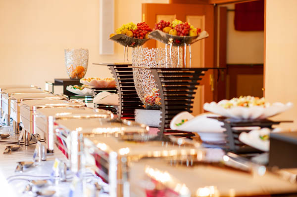 Festlich gedecktes Hochzeitsmenü Buffet mit warmen Speisen in Chafing Dishes für eine luxuriöse Hochzeit.